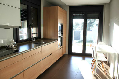 Diseño de cocina lineal minimalista de tamaño medio abierta con fregadero de un seno, puertas de armario de madera oscura, salpicadero marrón, electrodomésticos con paneles y suelo de baldosas de porcelana