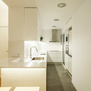 Modelo de cocina en L, contemporánea, de tamaño medio, abierta, con fregadero bajoencimera, armarios con paneles lisos, puertas de armario blancas, encimera de cuarzo compacto, salpicadero blanco, electrodomésticos blancos, suelo de baldosas de cerámica y suelo gris