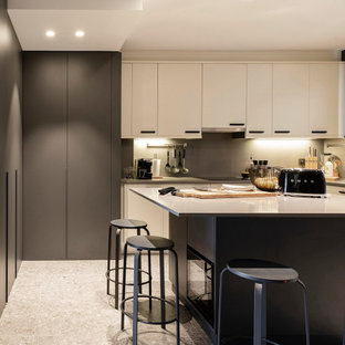 Diseño de cocina en L, actual, grande, abierta, con armarios con paneles lisos, puertas de armario beige, encimera de cuarzo compacto, una isla, salpicadero verde, suelo gris y encimeras blancas