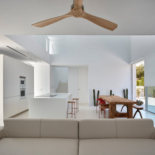 Foto de cocina minimalista, abierta, con armarios con paneles lisos, puertas de armario blancas, electrodomésticos blancos, suelo de cemento, una isla, suelo blanco y encimeras blancas