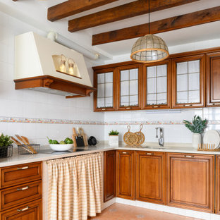 Foto de cocina en L, mediterránea, de tamaño medio, con fregadero bajoencimera, armarios con paneles con relieve, puertas de armario de madera oscura, salpicadero blanco, salpicadero de azulejos de porcelana, suelo de baldosas de porcelana, suelo beige y encimeras beige