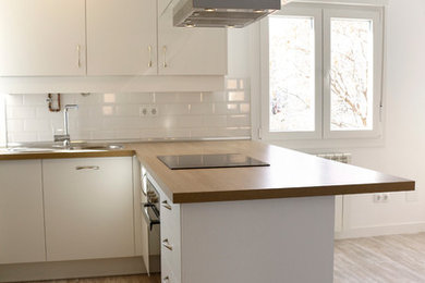 Inredning av ett nordiskt mellanstort kök, med en enkel diskho, släta luckor, vita skåp, träbänkskiva, vitt stänkskydd, stänkskydd i keramik, rostfria vitvaror, mellanmörkt trägolv och en halv köksö
