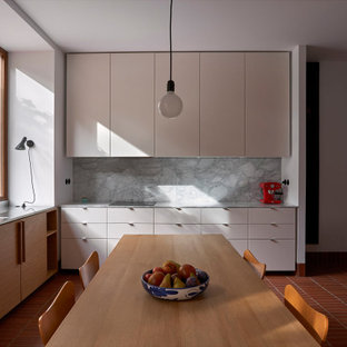 Ejemplo de cocina comedor en L, mediterránea, sin isla, con fregadero bajoencimera, armarios con paneles lisos, puertas de armario beige, salpicadero verde, suelo rojo y encimeras grises