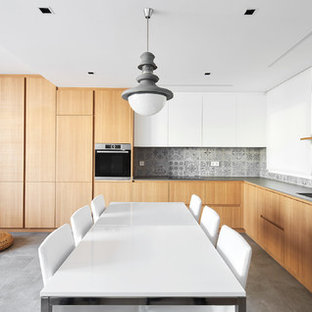 Imagen de cocina en L, contemporánea, abierta, con armarios con paneles lisos, puertas de armario de madera oscura, salpicadero verde, suelo gris, encimeras grises y fregadero bajoencimera
