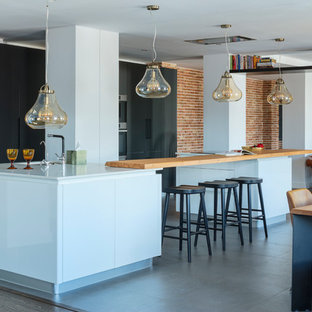 Modelo de cocina en U, contemporánea, grande, abierta, con armarios con paneles lisos, puertas de armario negras, encimera de cuarzo compacto, electrodomésticos con paneles, suelo de baldosas de cerámica, dos o más islas, suelo gris, encimeras blancas y fregadero bajoencimera