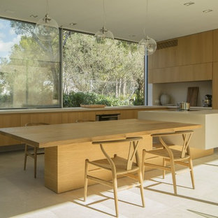 Ejemplo de cocina en L, moderna, con armarios con paneles lisos, puertas de armario de madera clara, una isla, suelo beige, fregadero bajoencimera, encimera de cemento, salpicadero de vidrio, electrodomésticos con paneles y encimeras grises