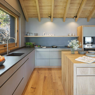 This is an example of a large country open plan kitchen in Other with light hardwood floors, limestone benchtops and with island.