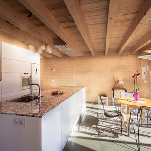 Ejemplo de cocina comedor lineal, campestre, de tamaño medio, con armarios con paneles lisos, puertas de armario blancas, encimera de granito, electrodomésticos blancos, una isla, suelo gris, fregadero encastrado y suelo de cemento