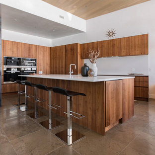 Modelo de cocina en L, moderna, grande, abierta, con suelo de mármol, suelo marrón, armarios con paneles lisos, puertas de armario de madera oscura, electrodomésticos negros, una isla y encimeras blancas