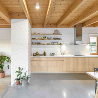 Ejemplo de cocina comedor lineal, actual, grande, con fregadero integrado, armarios con paneles lisos, puertas de armario de madera clara, salpicadero blanco, salpicadero de ladrillos, electrodomésticos de acero inoxidable, suelo gris y encimeras blancas