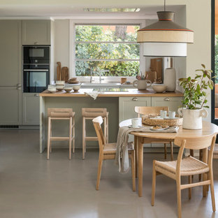 Foto de cocina comedor mediterránea, de tamaño medio, con puertas de armario grises, encimera de madera, suelo de cemento, península, suelo gris, fregadero bajoencimera, armarios estilo shaker y electrodomésticos negros