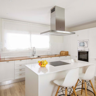 Foto de cocina en U, mediterránea, con fregadero encastrado, armarios estilo shaker, puertas de armario blancas, encimera de madera, electrodomésticos de acero inoxidable, suelo de madera en tonos medios, una isla, suelo marrón y encimeras marrones