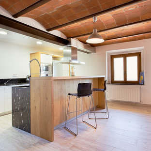 Imagen de cocina lineal, minimalista, con armarios con paneles lisos, puertas de armario blancas, salpicadero negro, electrodomésticos de acero inoxidable, una isla y encimeras negras