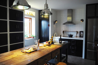 Foto de cocina lineal industrial de tamaño medio abierta y de obra con armarios con paneles lisos, una isla y puertas de armario negras