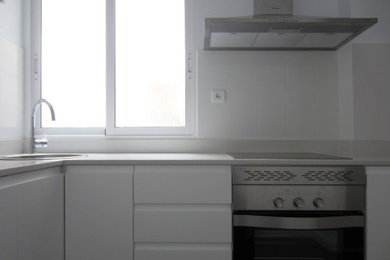 Foto de cocinas en L nórdica pequeña cerrada con fregadero de un seno, armarios con paneles lisos, puertas de armario blancas, suelo de baldosas de cerámica y suelo gris