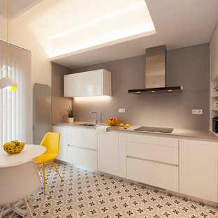 Ejemplo de cocina comedor en L, moderna, de tamaño medio, sin isla, con fregadero de un seno, armarios con paneles lisos, puertas de armario blancas, encimera de cuarzo compacto, salpicadero verde, electrodomésticos negros, suelo de baldosas de cerámica y suelo multicolor