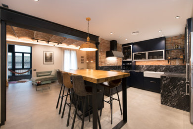 Photo of a large urban u-shaped open plan kitchen in Other with a single-bowl sink, flat-panel cabinets, blue cabinets, granite worktops, black splashback, granite splashback, black appliances, porcelain flooring, an island, grey floors and black worktops.