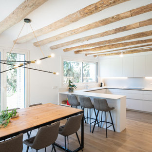 Imagen de cocina en U, actual, con armarios con paneles lisos, puertas de armario blancas, suelo de madera clara, península y suelo beige