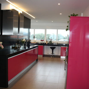 Large contemporary single-wall open plan kitchen in Bilbao with an undermount sink, flat-panel cabinets, red cabinets, granite benchtops, black splashback, stainless steel appliances, porcelain floors and no island.