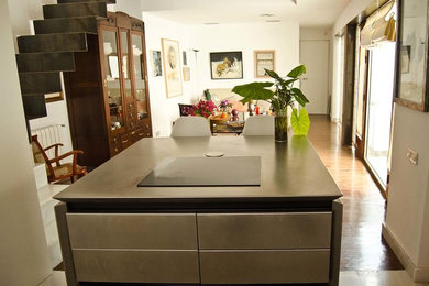 Imagen de cocina lineal contemporánea abierta con armarios con paneles lisos, puertas de armario en acero inoxidable, encimera de acero inoxidable y una isla