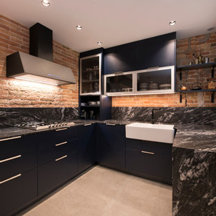 Foto de cocina en U, urbana, grande, abierta, con fregadero de un seno, armarios con paneles lisos, puertas de armario azules, encimera de granito, salpicadero negro, puertas de granito, electrodomésticos negros, suelo de baldosas de porcelana, una isla, suelo gris y encimeras negras