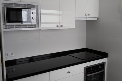Foto de cocina moderna de tamaño medio cerrada con fregadero sobremueble, puertas de armario blancas, encimera de granito y encimeras negras