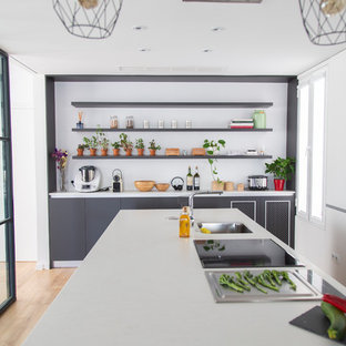 Imagen de cocina contemporánea, grande, cerrada, con puertas de armario blancas, encimera de cuarzo compacto, una isla, encimeras blancas, fregadero bajoencimera, armarios con paneles lisos, suelo de madera clara y suelo beige