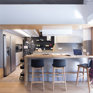 Foto de cocina en U, contemporánea, con península, armarios con paneles lisos, puertas de armario blancas, encimera de madera, salpicadero verde, salpicadero de vidrio templado, electrodomésticos de acero inoxidable, suelo beige y encimeras beige