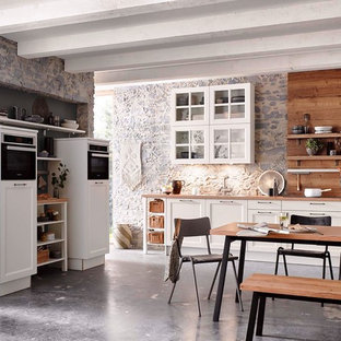 Diseño de cocina nórdica, abierta, con puertas de armario blancas, encimera de madera y salpicadero de madera