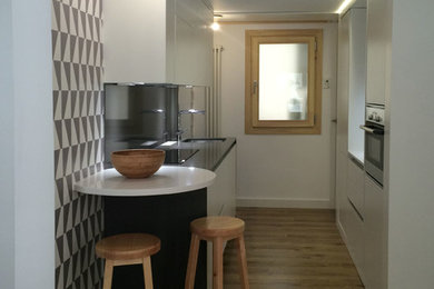 Modelo de cocina comedor lineal minimalista de tamaño medio sin isla con armarios con paneles lisos, puertas de armario blancas y suelo de madera en tonos medios