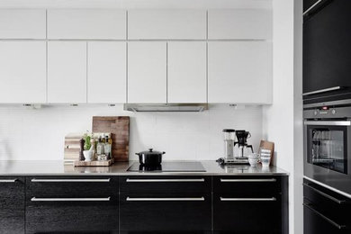 Modelo de cocina lineal contemporánea de tamaño medio abierta sin isla con armarios con paneles lisos, puertas de armario negras y electrodomésticos de acero inoxidable