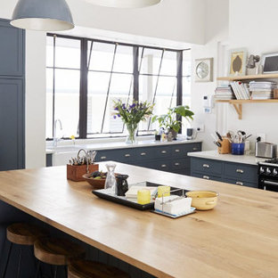 Ejemplo de cocina en U, tradicional renovada, extra grande, con fregadero sobremueble, armarios con paneles lisos, puertas de armario azules, salpicadero de vidrio, electrodomésticos de acero inoxidable, una isla, suelo gris y encimeras blancas