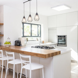 Foto de cocina en U, actual, grande, abierta, con fregadero bajoencimera, armarios con paneles lisos, puertas de armario blancas, encimera de cuarzo compacto, electrodomésticos de acero inoxidable, suelo de baldosas de porcelana, una isla, suelo beige, encimeras blancas y salpicadero blanco