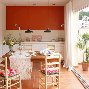 Modelo de cocina comedor mediterránea con armarios con paneles lisos, puertas de armario blancas, salpicadero beige, encimeras beige, fregadero bajoencimera y suelo naranja