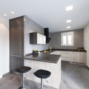 Imagen de cocina en U, actual, de tamaño medio, con armarios con paneles lisos, puertas de armario de madera clara, península, suelo gris, encimeras marrones, fregadero encastrado, salpicadero verde y electrodomésticos con paneles