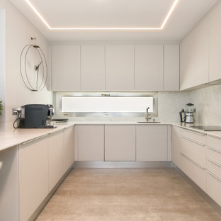 Diseño de cocina en U, contemporánea, de tamaño medio, con fregadero bajoencimera, armarios con paneles lisos, puertas de armario blancas, salpicadero blanco, electrodomésticos de acero inoxidable, suelo de baldosas de porcelana, península, suelo gris y encimeras blancas