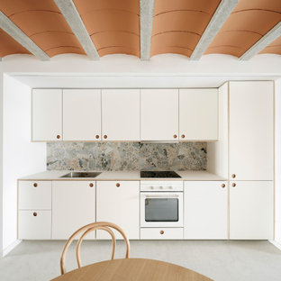 Imagen de cocina lineal, escandinava, pequeña, abierta, sin isla, con fregadero encastrado, armarios estilo shaker, puertas de armario blancas, encimera de laminado, salpicadero multicolor, salpicadero de azulejos de cerámica, electrodomésticos de acero inoxidable, suelo de cemento, suelo gris y encimeras blancas