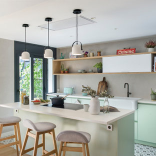 Ejemplo de cocina de galera, contemporánea, abierta, con fregadero sobremueble, armarios con paneles lisos, puertas de armario verdes, salpicadero verde, electrodomésticos de acero inoxidable, una isla, suelo multicolor y encimeras blancas