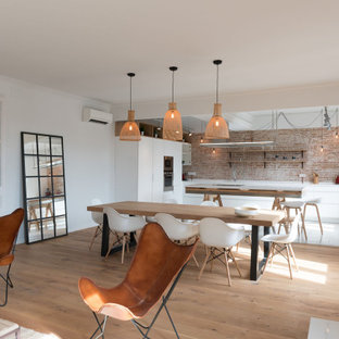 Foto de cocina en L, escandinava, grande, abierta, con fregadero bajoencimera, armarios con paneles lisos, puertas de armario blancas, salpicadero rojo, salpicadero de ladrillos, electrodomésticos con paneles, una isla, suelo blanco y encimeras blancas