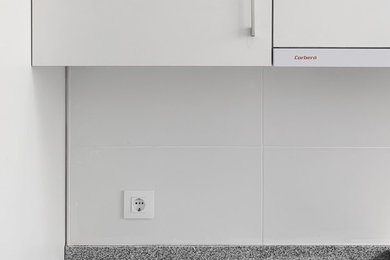 Diseño de cocina lineal pequeña cerrada con puertas de armario blancas, encimera de granito, suelo de baldosas de porcelana y suelo gris