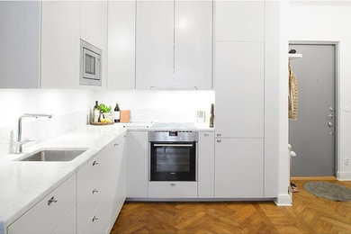 Imagen de cocinas en L contemporánea de tamaño medio abierta sin isla con armarios con paneles lisos, puertas de armario blancas, encimera de laminado y salpicadero blanco