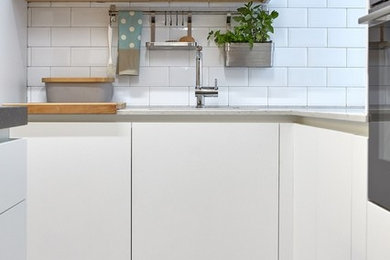 This is an example of a medium sized scandi single-wall open plan kitchen in Madrid with a submerged sink, flat-panel cabinets, white cabinets, quartz worktops, white splashback, porcelain splashback, stainless steel appliances and an island.