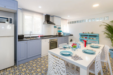 Immagine di una cucina stile marinaro di medie dimensioni con ante con riquadro incassato, ante blu, paraspruzzi bianco, pavimento con piastrelle in ceramica, nessuna isola e pavimento multicolore