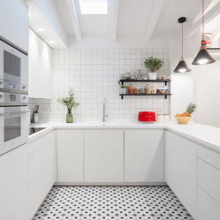 Diseño de cocina en U, actual, con fregadero integrado, armarios con paneles lisos, puertas de armario blancas, salpicadero blanco, electrodomésticos blancos, península, suelo multicolor y encimeras blancas