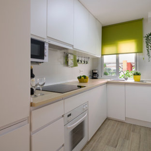 Diseño de cocina en L, contemporánea, cerrada, sin isla, con fregadero encastrado, armarios con paneles lisos, puertas de armario de madera clara, encimera de madera, salpicadero blanco, electrodomésticos con paneles, suelo de madera clara, suelo beige y encimeras beige