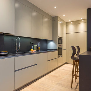Imagen de cocina en L, actual, de tamaño medio, abierta, con fregadero integrado, armarios con paneles lisos, puertas de armario beige, encimera de cuarzo compacto, salpicadero negro, electrodomésticos de acero inoxidable, suelo de madera clara y suelo beige