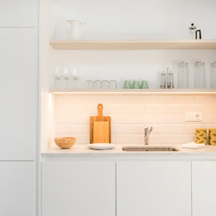 Diseño de cocina lineal, contemporánea, pequeña, con fregadero bajoencimera, armarios con paneles lisos, puertas de armario blancas, encimera de mármol, salpicadero blanco, salpicadero de azulejos tipo metro y electrodomésticos con paneles