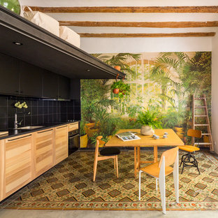 Imagen de cocina comedor lineal, tropical, de tamaño medio, sin isla, con fregadero bajoencimera, puertas de armario de madera oscura, salpicadero negro, salpicadero de azulejos de cerámica, electrodomésticos negros, suelo de baldosas de cerámica, suelo multicolor y armarios con paneles lisos