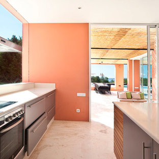 Ejemplo de cocina mediterránea con armarios con paneles lisos, puertas de armario grises, electrodomésticos de acero inoxidable, una isla, suelo blanco, salpicadero verde y encimeras grises
