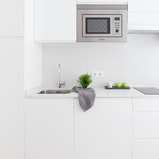 Imagen de cocina lineal, nórdica, pequeña, abierta, sin isla, con fregadero bajoencimera, armarios con paneles lisos, puertas de armario blancas, encimera de cuarzo compacto, salpicadero blanco, salpicadero de piedra caliza, electrodomésticos de acero inoxidable, suelo de madera clara, suelo beige y encimeras blancas